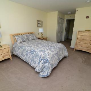 A cozy bedroom featuring a bed with patterned bedding, wooden furniture, and soft lighting.