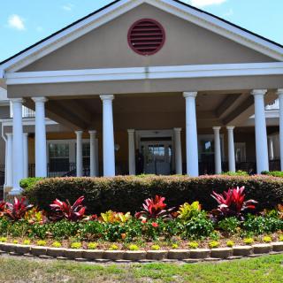 A large building with a columned entrance and landscaped flower beds.