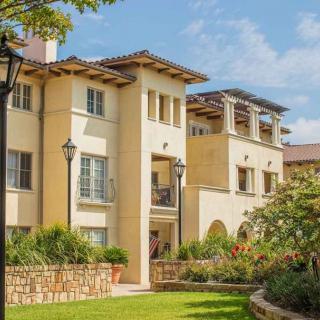 A modern residential apartment building surrounded by a well-maintained garden on a sunny day.