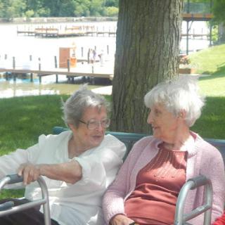 Two elderly women enjoying a peaceful moment together in a park.