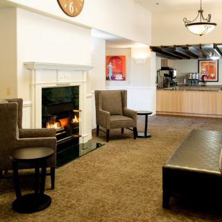A cozy lobby area featuring a fireplace, armchairs, and a coffee table.