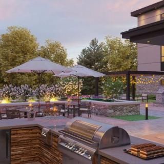A luxurious outdoor patio featuring a barbecue grill, dining area with umbrellas, and elegant evening lighting.