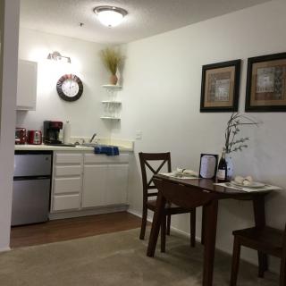 A cozy kitchen and dining area with a small table and chairs, featuring wall art and modern decor.