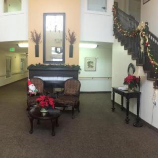 A cozy lobby decorated for the holidays with chairs, a table, poinsettias, and a staircase adorned with garlands.