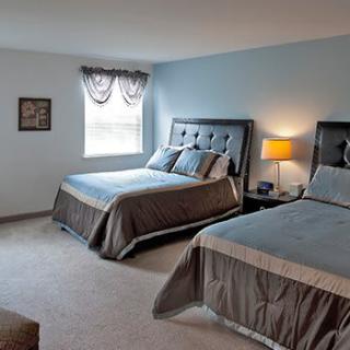 A cozy bedroom with two beds, a lamp, and a window allowing natural light.