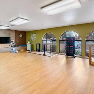 A spacious and well-lit rehabilitation room designed for physical therapy and exercise.