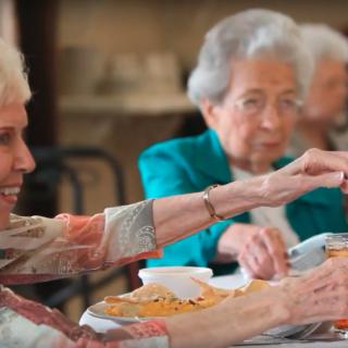 Elderly women enjoying a meal together in a community setting.