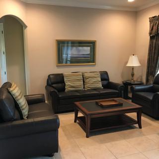 A cozy living room with black sofas, a coffee table, and a lamp.