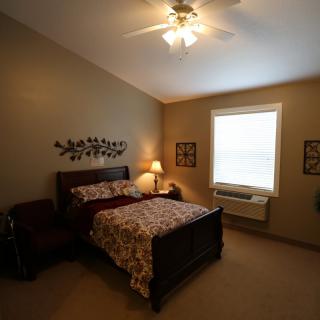 Cozy bedroom with a wooden bed, bedside lamp, and window.