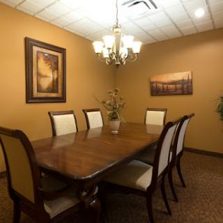 A well-appointed conference room featuring a large dining table, elegant chairs, and decorative artwork on the walls.