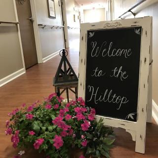 A welcoming chalkboard sign with flowers and a decorative lantern in a hallway.
