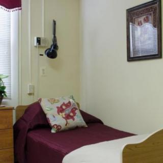A cozy bedroom with a single bed, decorative pillow, and wall art.