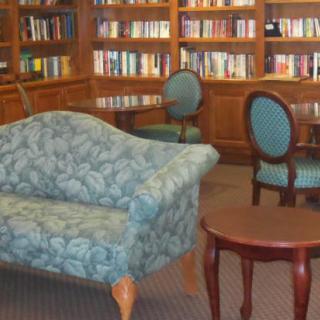 A cozy library corner featuring a comfortable couch, elegant chairs, and well-stocked bookshelves.