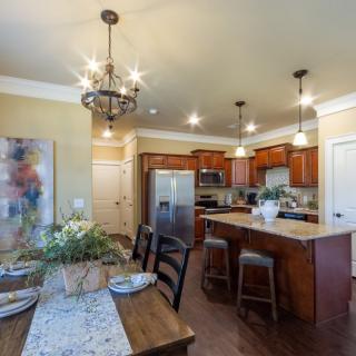 A modern kitchen and dining area with wooden cabinets, an island counter, and stylish lighting fixtures.