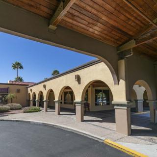 A sunny view of a building exterior featuring arches and palm trees.