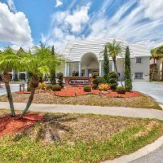A view of a landscaped entrance to a building with palm trees and a clear blue sky.