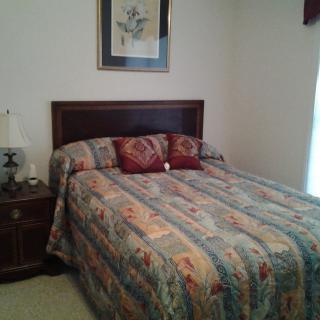 A cozy bedroom with a quilted bedspread and decorative pillows.