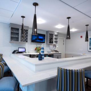 A modern kitchen interior with stylish pendant lighting and striped chairs around a sleek countertop.
