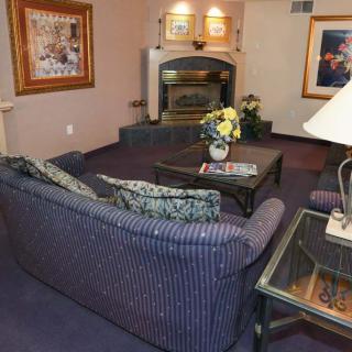 A cozy living room with a striped sofa, coffee table, and a fireplace accented by artwork on the walls.
