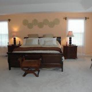 A cozy bedroom with a large bed and matching wooden furniture, softly lit by bedside lamps.