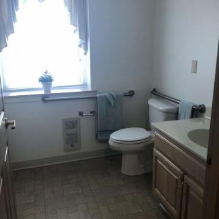 A bright bathroom with a toilet, sink, and neatly arranged towels by the window.