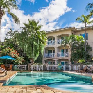 A tropical residential area with a pool surrounded by palm trees and clear skies.