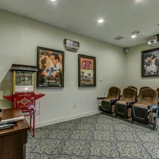 A cozy home theater room with movie posters, a popcorn machine, and comfortable seating.