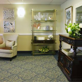 A cozy living room area featuring an armchair, a decorative shelf, and artwork on the walls.
