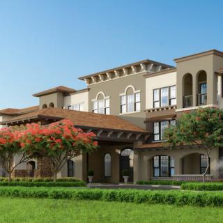 A Mediterranean-style building with lush landscaping and a clear blue sky.