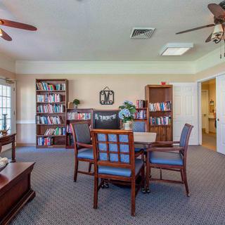 A cozy library room with bookshelves, a table, and chairs.