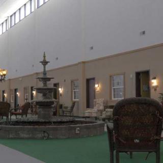 A spacious indoor area featuring a central fountain surrounded by chairs and ambient lighting.