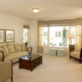 A spacious living room with comfortable seating and large windows providing natural light.