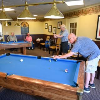A group of people playing billiards in a recreational room.
