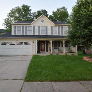 A suburban house with a front porch and garage, surrounded by trees.