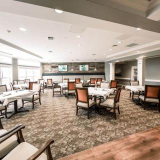 An empty dining area with neatly arranged tables and chairs, featuring large windows and elegant decor.