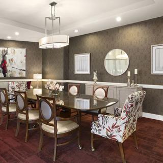 Elegant dining room with a modern chandelier, a large table surrounded by stylish chairs, and decorative wall elements.
