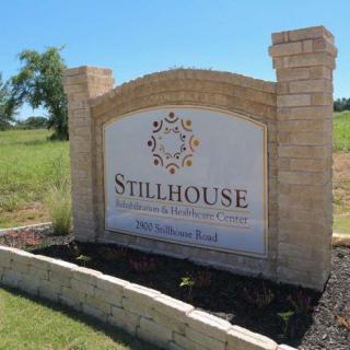 A stone entrance sign for Stillhouse on a grassy landscape.