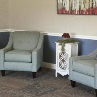 A cozy seating area featuring two light blue chairs and a white side table adorned with decorative elements.