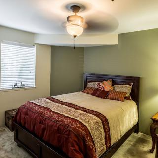 A cozy bedroom with a comfortable bed, ceiling fan, and soft lighting.