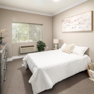 A modern bedroom with white bedding and minimalist decor.