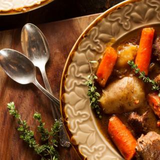 A hearty stew with carrots and potatoes, garnished with fresh herbs.