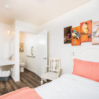 A modern bedroom with colorful artwork and a view into the bathroom.
