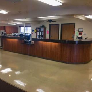 A reception desk in an office with a clean, polished floor and overhead lighting.