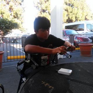 A young boy seated at an outdoor table, focused on playing.