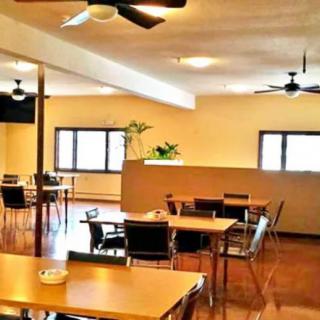 A spacious dining area with tables, chairs, and ceiling fans.