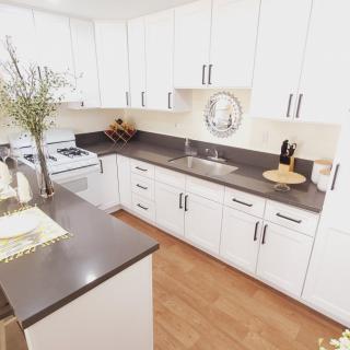 A modern kitchen with white cabinets and a sleek gray countertop.