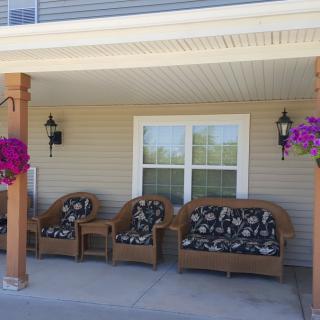 A cozy porch with wicker furniture and vibrant hanging flowers.