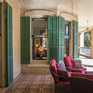A cozy patio area with red-cushioned seating, green shutters, and vintage tiles.