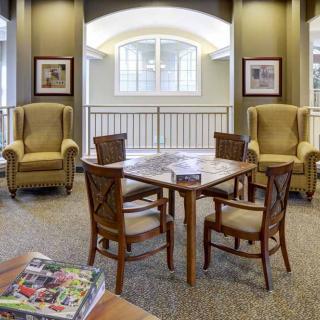 A cozy living room with upholstered chairs, a wooden table, and decorative elements by a window.
