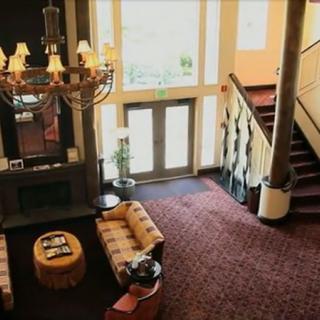 A spacious hotel lobby featuring a grand chandelier, comfortable seating area, and a staircase.